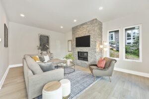living room with couch, chair and large tv hung on stone fireplace