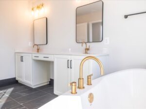 Dual bathroom vanity with a custom bathtub and gold fixtures in the foreground